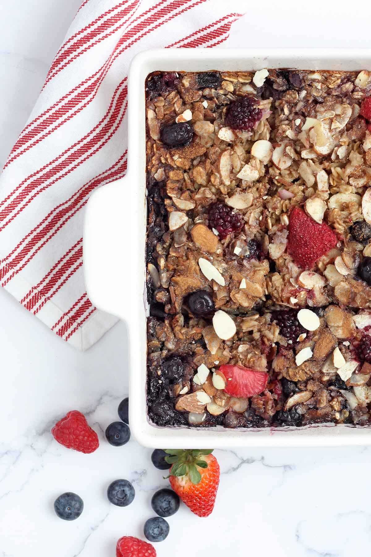 a white ceramic dish filled with baked oatmeal and fresh berries