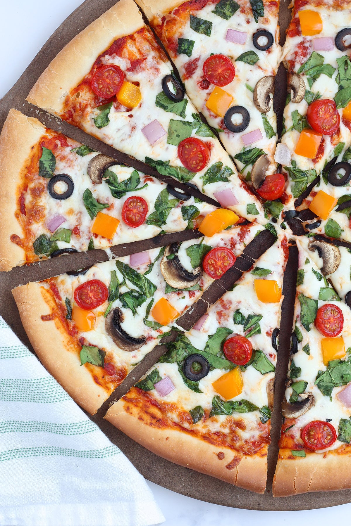 A close up picture of veggie pizza on a stone pizza pan.