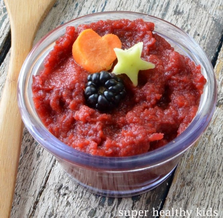 a small bowl filled with red fruit puree and topped with fresh fruit