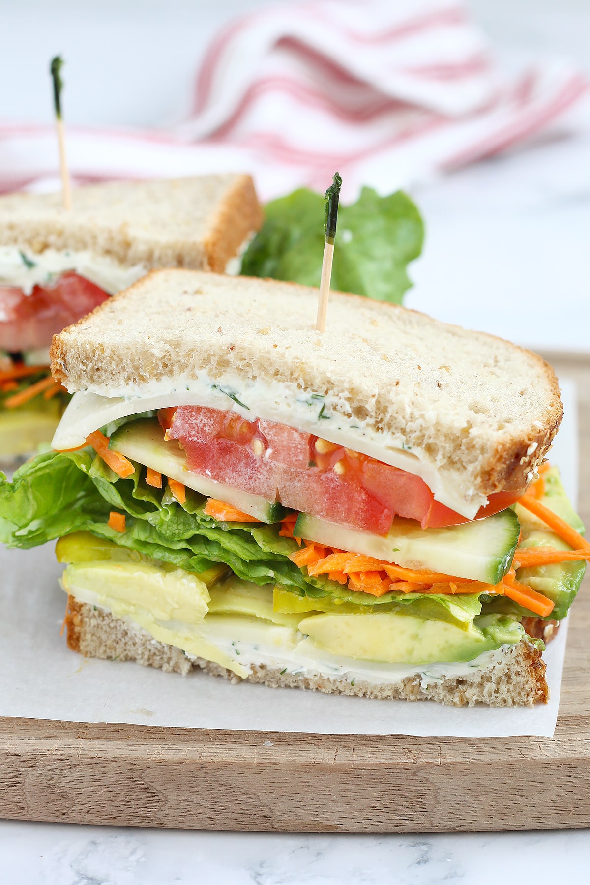 A veggie sandwich on whole wheat bread, set on a parchment lined cutting board.